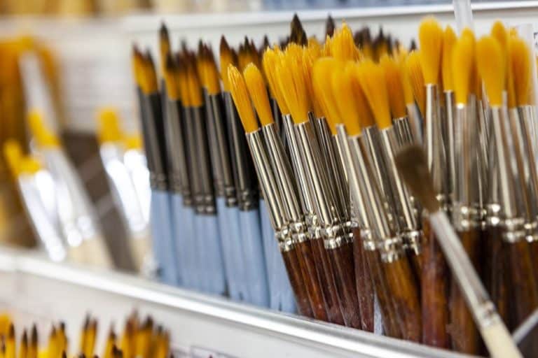 A selection of oil paint brushes laid out, highlighting the differences in brush head size and shape.